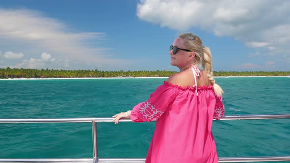 Young Blond Woman in Pink Dress and Sunglasses on Catamaran Yacht