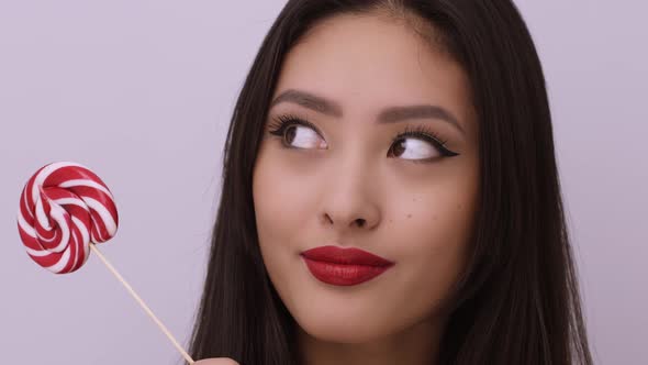 Fashion Portrait of Asian Woman with Lollipop in Studio