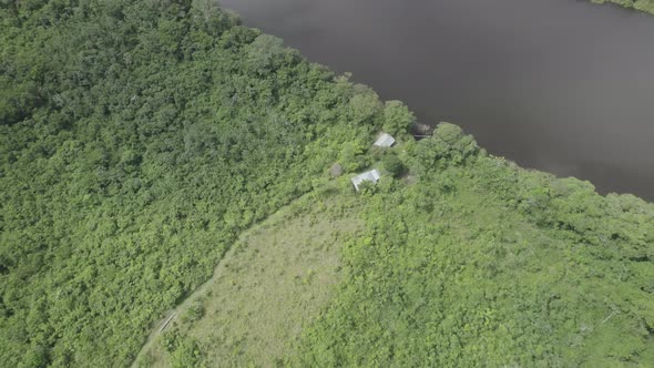 Aerial View Of Isolated Structure Near Rivershore With Dense Tropical Forest In Colombia.