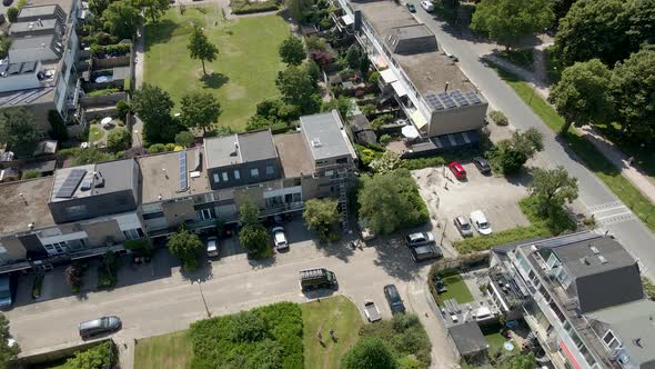 Drone pulling back from row of houses in a suburban neighborhood and revealing a small town in summe