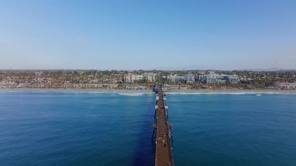 people walk along huge wooden pier of Oceanside beach town, in San Diego county, CA. aerial