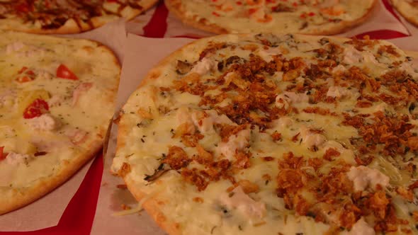 Appetizing Small Pizza Spinning on Background of Other Pizzas