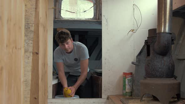 Young man bailing out water from inside wooden boat