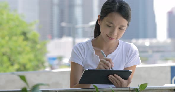 Woman drawing on digital tablet at park 