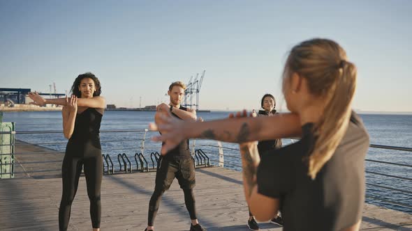 Group of Diverse People Working Out Outdoors Repeating Warm Up Exercises After Fitness Coach