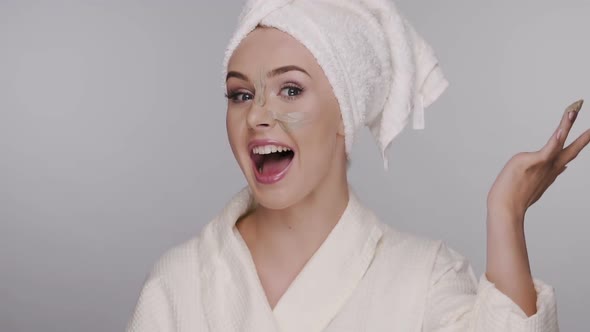 Surprised and Happy Girl Applies Face Mask in Bath Robe