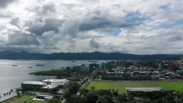 Lowering aerial of cityscape on main island of Fiji, dramatic sky above horizon