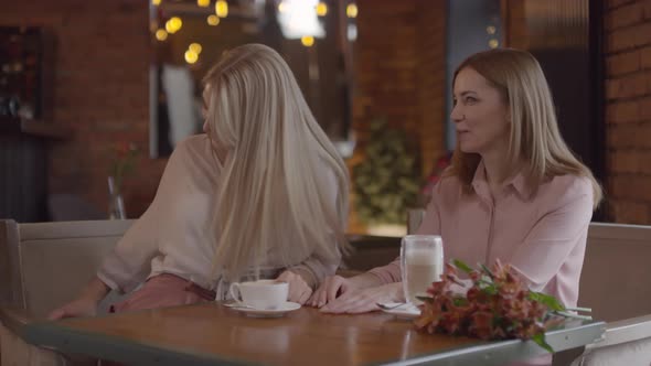 Happy Woman Giving Present to Mother in Cafe