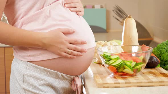 Closeup of Pregnant Woman with Big Belly Standing on Kitchen and Touching Big Abdomen