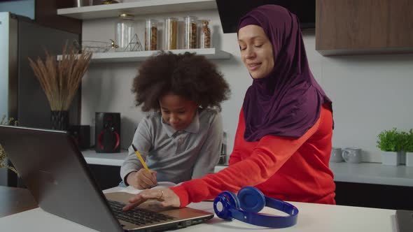 Caring Muslim Mother Helping Multiracial School Age Daughter with Homework at Home