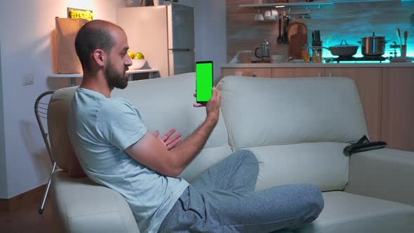 Focused Man Talking with His Friends on Smartphone with Mock Up Green Screen Chroma Key Display