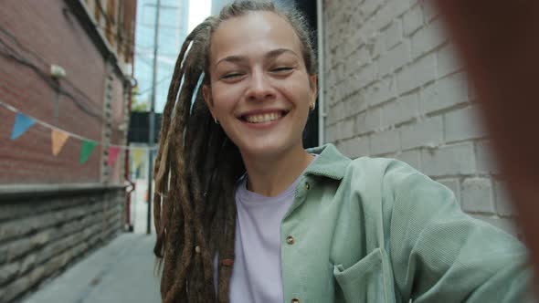 POV of Attractive Girl with Dreadlocks Speaking and Waving Hand Looking at Camera Making Video Call