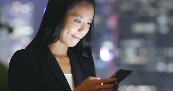 Businesswoman using smart phone in city at night 