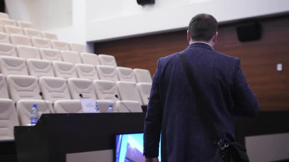 A Man in a Jacket Walks Through a Conference Room