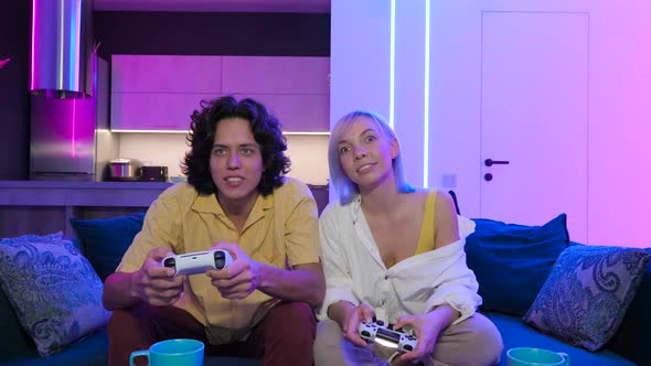 Handsome Young Man Teaching How To Play the Video Games To His Girlfriend on the Couch Concept About