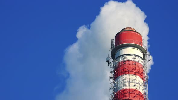 A Smokestack Emits Smoke - Closeup - the Clear Blue Sky in the Background