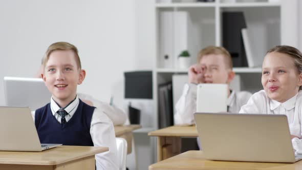 Excited Schoolchildren Listening to Teacher at Lesson