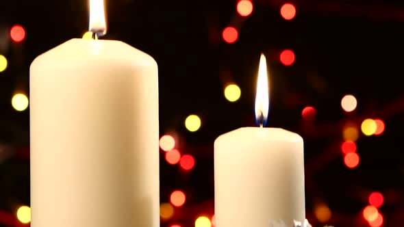 Two Big White Candles with Christmas Decorations Like Red Bow, Balls and Tree on Black, Bokeh, Light