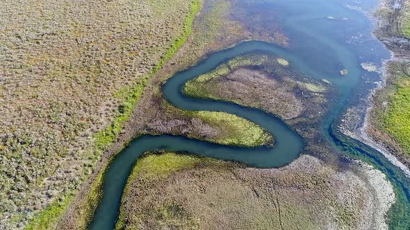 Flying over winding river as it flows into reservoir