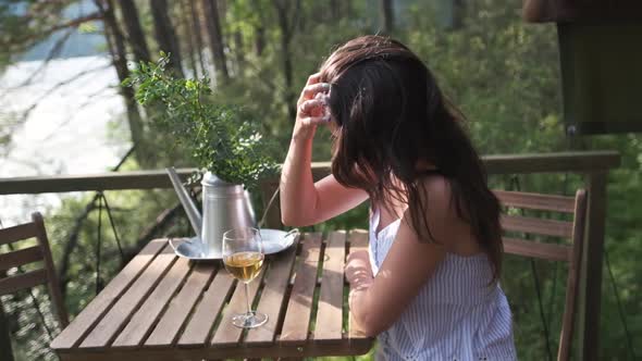 Attractive Brunette with a Glass in Her Hands Enjoying Nature in the Mountains, Sitting on the