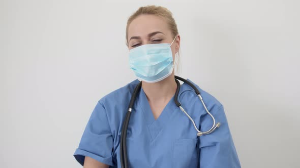 Female Nurse or Doctor. Young Pretty Woman in Blue Clothes with Medical Mask Posing