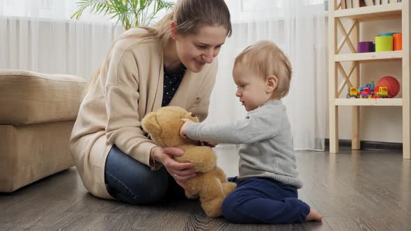 Baby boy with mother playing with teddy bear