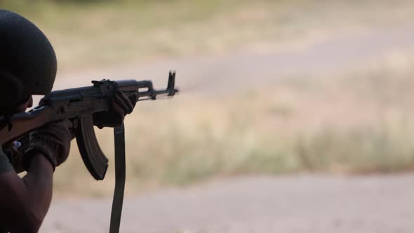 Military Man in Green Uniform Vest Unloading Gun with Machine Gun in Hand Soldier Lying on Ground