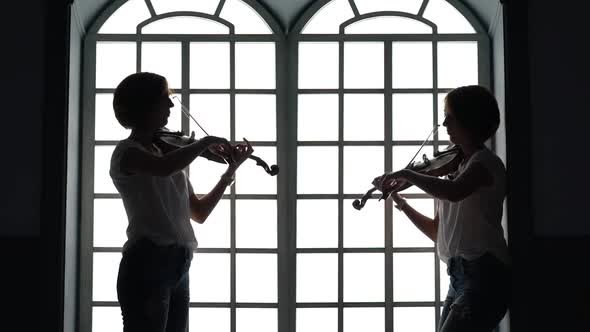 Musican Plays the Violin in the Evening Against the Background of a Window. Silhouette