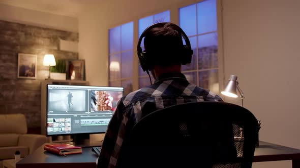 Back View of Videographer with Headset Working Late at Night on a New Project