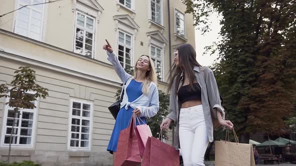 Attractive Carefree Women with Various Shop Bags Walking Down the Urban Street