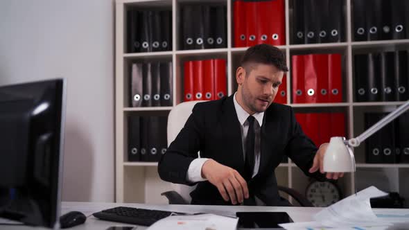 Tired Businessman with Documents Falling Asleep in Office