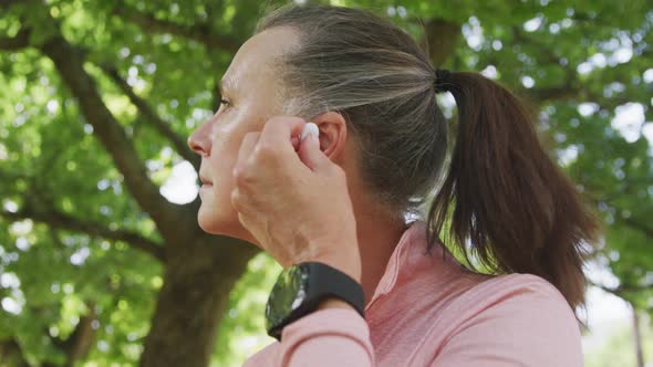 Senior woman using wireless earphones in the park