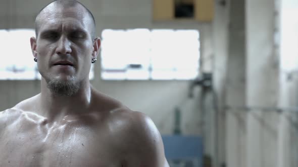 Portrait of a shirtless personal trainer man inside an abandoned building after a workout