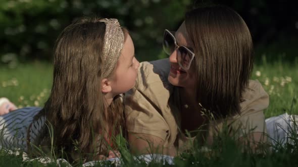 Summer Portrait of Mom and Preschool Daughter Lying on the Grass in the Park