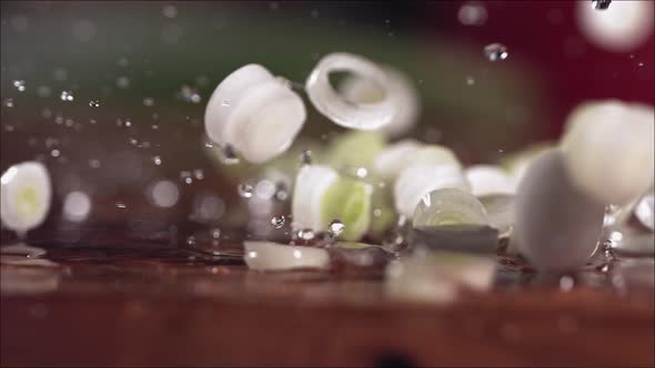 Falling of Chopped Fresh Green Onions on a Cutting Board in Slow Motion