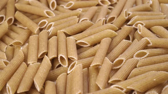 Heap of integral whole grain healthy uncooked penne pasta