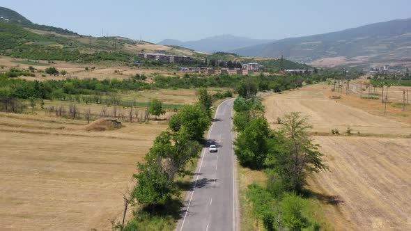 Aerial view car on highway. Aerial footage white, soviet style Russian car on highway on road.