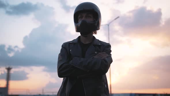 Portrait of Young Man in Helmet Standing Near Motorbike on Beautiful Sunset Sky Background Close Up