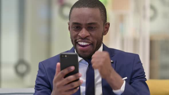 Portrait of African Businessman Celebrating Success on Smartphone