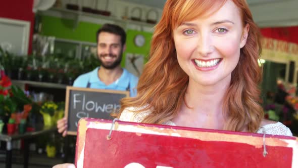 Florists holding signboards in flower shop