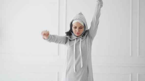 Muslim Woman in Hijab and Fitness Dress Is Warming Before Training.