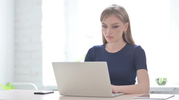 Woman Smiling at Camera While Using Laptop