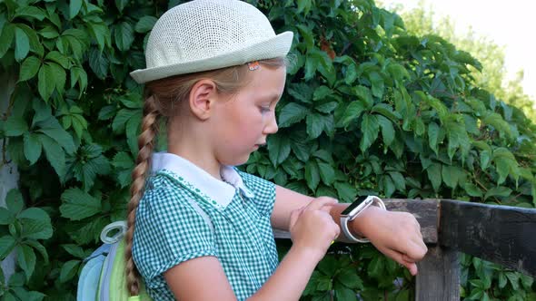 Child schooler using smartwatch outdoor park. Kid talking on vdeo call with parents on smartwatch