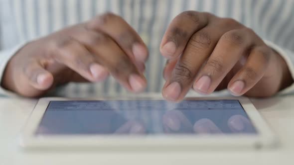 Close Up of African Man Typing on Digital Tablet