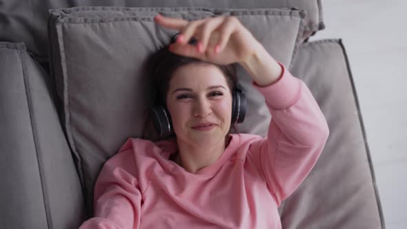 Woman Relaxing on Comfortable Sofa Listening to the Music in Headphones