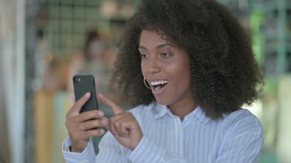 Portrait of Excited African Businesswoman Celebrating Success on Smartphone