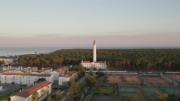 Vila Real de Santo António Lighthouse against lush coastal forest. Ocean on the horizon. Aerial pede