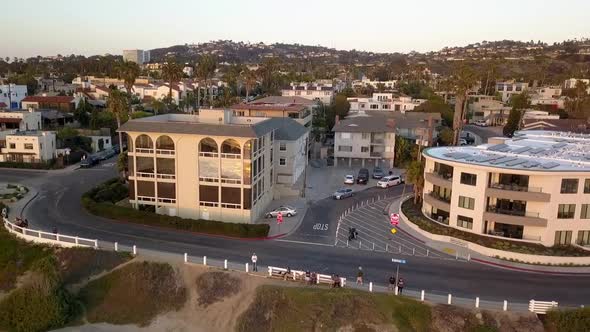 A small town by the sea, many houses and palm trees. Dramatic aerial view flight fly backwards drone