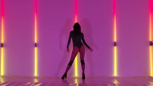 Back View Young Adult Woman Dancing Modern and Sensual Plastic Strip Dance in Dark Studio