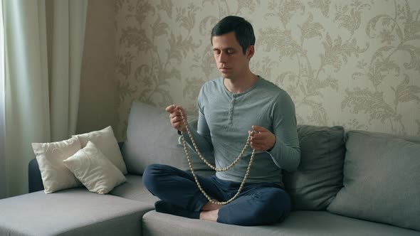 Man Meditates on a Beads at Home